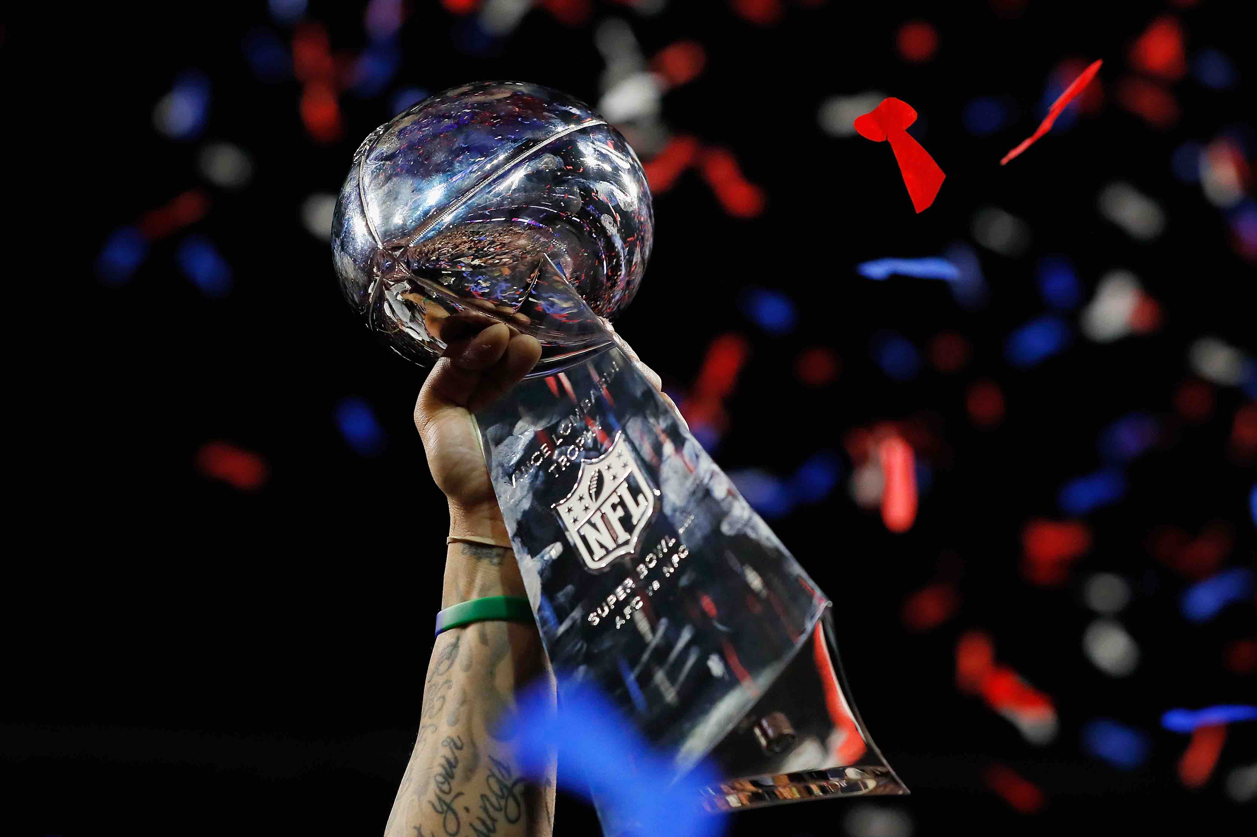 A detail of a New England Patriots player raising the Vince Lombardi Trophy at the Super Bowl