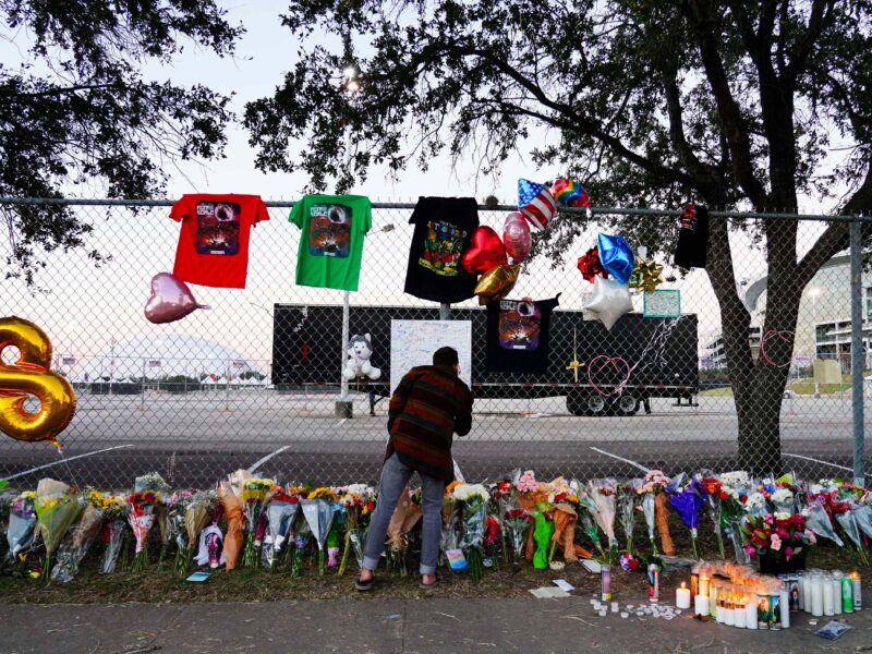 HOUSTON, TX - NOVEMBER 07: A visitor writes a note at a memorial outside of the canceled Astroworld festival at NRG Park on November 7, 2021 in Houston, Texas. According to authorities, eight people died and 17 people were transported to local hospitals after what was described as a crowd surge at the Astroworld festival, a music festival started by Houston-native rapper and musician Travis Scott in 2018.