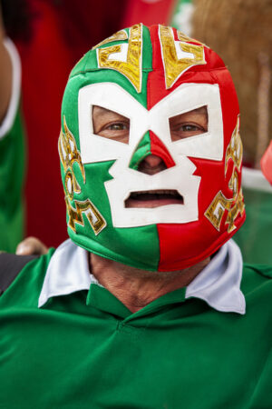 Front view portrait of Mexican football wearing Lucha Libre wrestling mask while watching international championship match at stadium