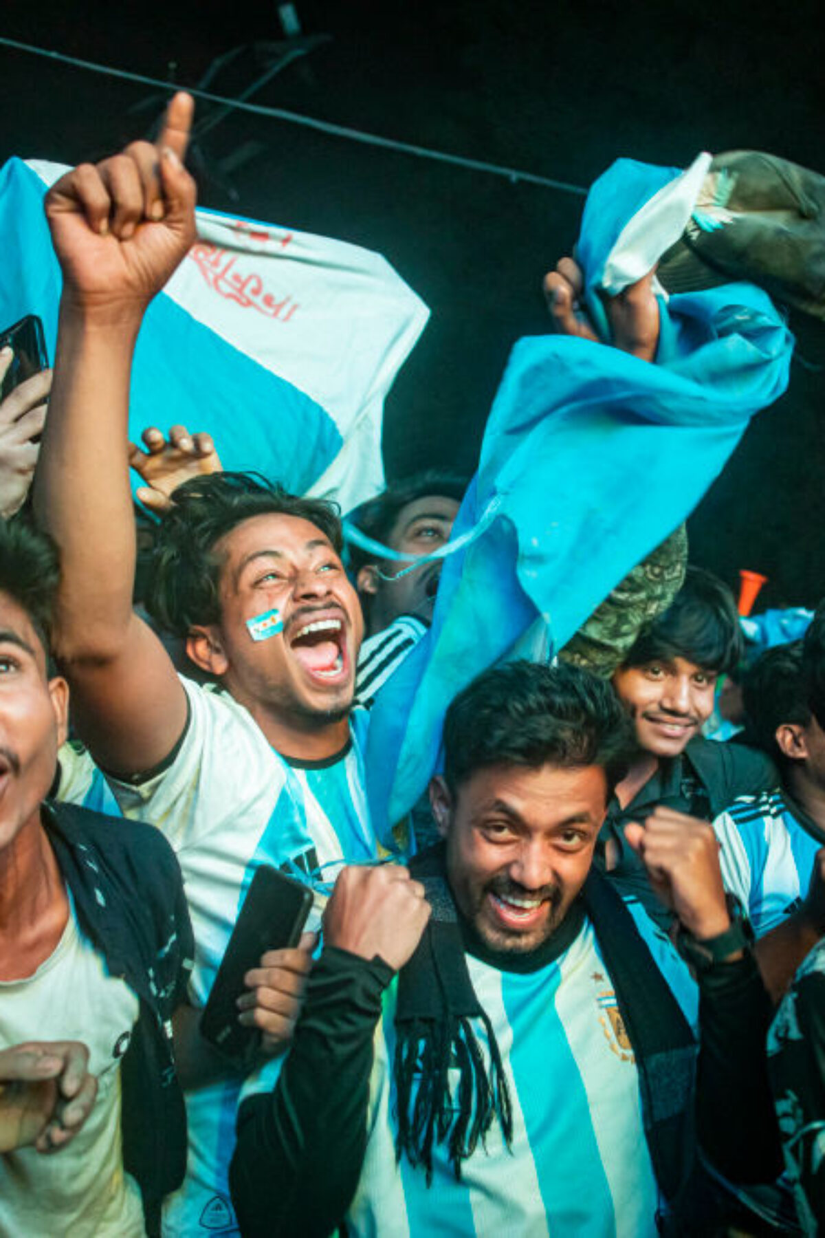 Football fans in Bangladesh celebrate after Argentina players scored a goal as they watch the Qatar 2022 World Cup Group C football match between Argentina and Poland on a big screen, the Dhaka University area, on December 1, 2022.