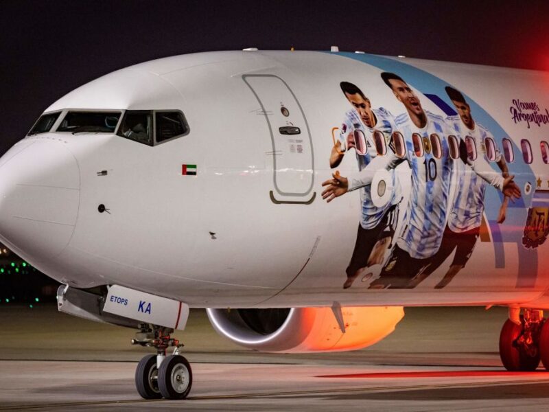 Members of the Argentinian team peer out from the windows on their plane adorned with a picture of Argentina's forward Lionel Messi and teammates as the team arrives at the Hamad International Airport in Doha on November 17, 2022, ahead of the Qatar 2022 World Cup football tournament. (Photo by Odd ANDERSEN / AFP) (Photo by ODD ANDERSEN/AFP via Getty Images)