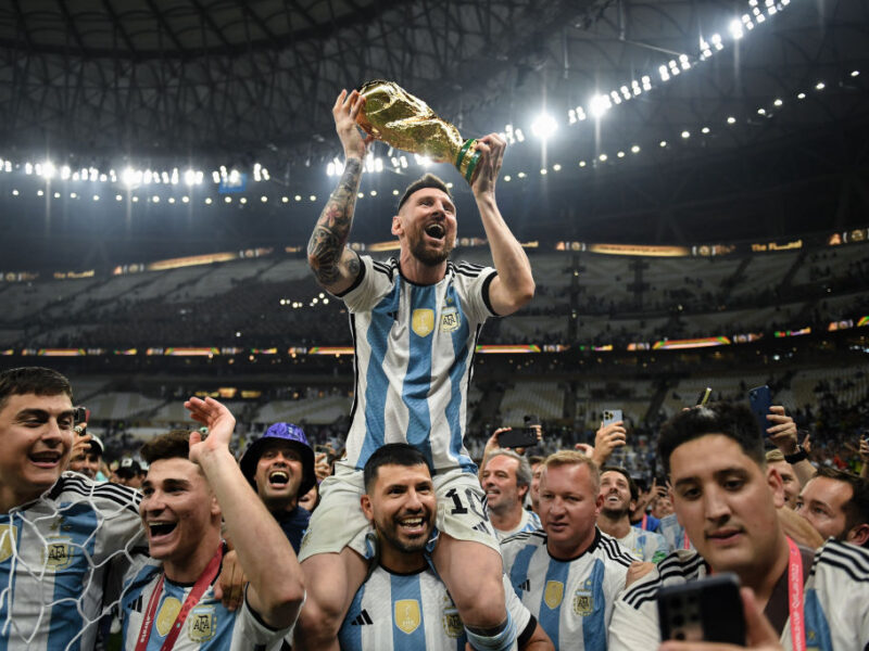 LUSAIL CITY, QATAR - DECEMBER 18: Lionel Messi of Argentina celebrates with the FIFA World Cup Qatar 2022 Winner's Trophy on Sergio 'Kun' Aguero's shoulders after the team's victory during the FIFA World Cup Qatar 2022 Final match between Argentina and France at Lusail Stadium on December 18, 2022 in Lusail City, Qatar. (Photo by David Ramos - FIFA/FIFA via Getty Images)