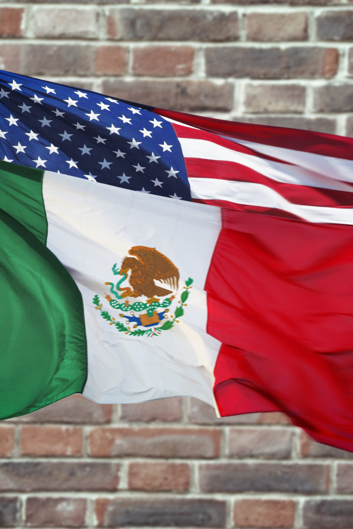 Mexican and American flag with wall behind