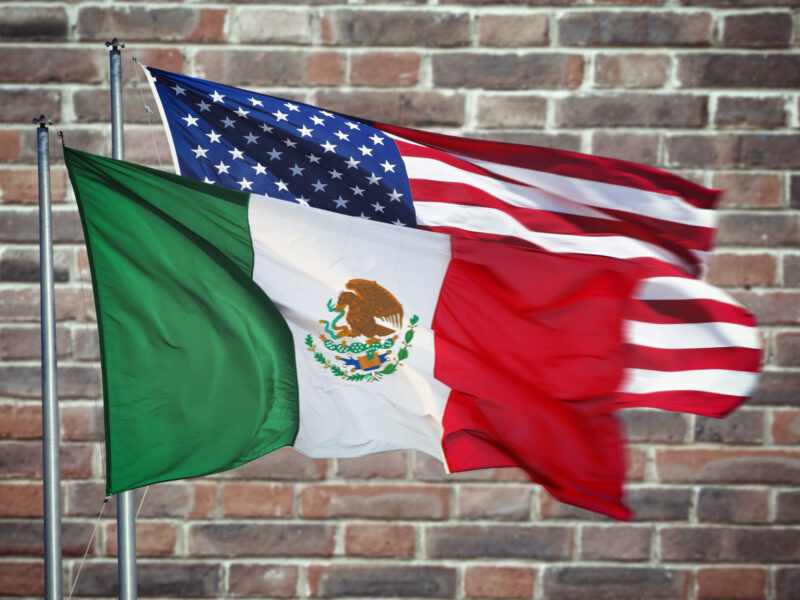 Mexican and American flag with wall behind