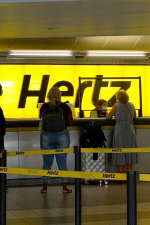 FORT LAUDERDALE, FLORIDA - OCTOBER 25: People stand at a Hertz car rental counter in the Fort Lauderdale-Hollywood International Airport on October 25, 2021 in Miami, Florida. Hertz announced that it ordered 100,000 Teslas as the company is emerging from bankruptcy. (Photo by Joe Raedle/Getty Images)