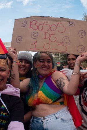 Demonstrators pose for a photo with a sign that reads free kisses of 1 or 3 at a time, during the international Pride parade celebrations in Bogota, Colombia, on July 3, 2022. Colombia celebrates the international pride parade the closest sunday to the international event to gather the most amount of members of the LGTBIQ+ Community. (Photo by: Perla Bayona/Long Visual Press/Universal Images Group via Getty Images)