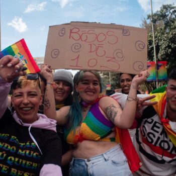 Demonstrators pose for a photo with a sign that reads free kisses of 1 or 3 at a time, during the international Pride parade celebrations in Bogota, Colombia, on July 3, 2022. Colombia celebrates the international pride parade the closest sunday to the international event to gather the most amount of members of the LGTBIQ+ Community. (Photo by: Perla Bayona/Long Visual Press/Universal Images Group via Getty Images)
