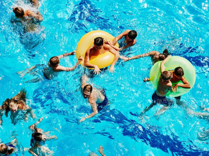 Group of kids playing together in outdoor pool overhead view