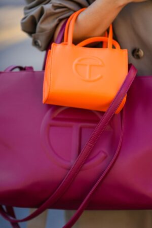 NEW YORK, NEW YORK - SEPTEMBER 14: Samia Laaboudi wears a beige long trench coat, a neon orange shiny leather handbag from Telfar, a burgundy shiny leather large handbag from Telfar, outside Michael Kors, during New York Fashion Week, on September 14, 2022 in New York City. (Photo by Edward Berthelot/Getty Images)