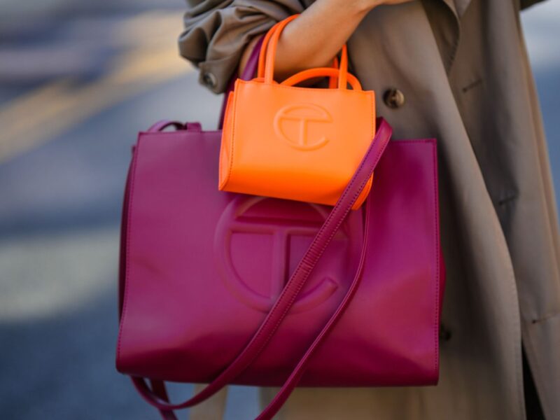 NEW YORK, NEW YORK - SEPTEMBER 14: Samia Laaboudi wears a beige long trench coat, a neon orange shiny leather handbag from Telfar, a burgundy shiny leather large handbag from Telfar, outside Michael Kors, during New York Fashion Week, on September 14, 2022 in New York City. (Photo by Edward Berthelot/Getty Images)