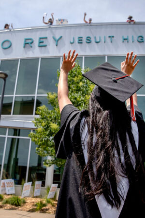 Graduation student waving at school.