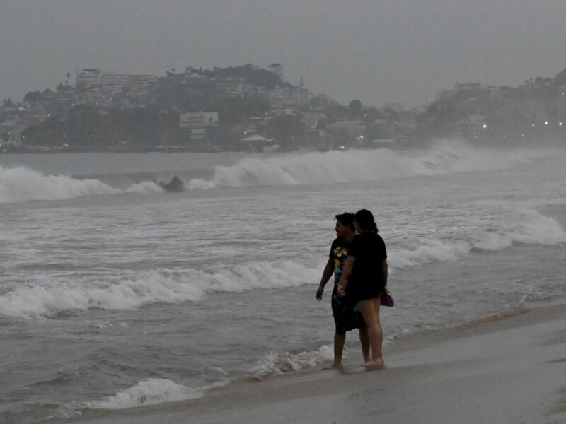 People stand on the beach after Hurricane Otis' arrival alert in Acapulco, Guerrero state, Mexico on October 24, 2023. A new Category 3 hurricane, driven by winds exceeding 200 km/h, threatens Acapulco, the tourist capital of the Pacific on the west coast of Mexico, the American National Hurricane Center (NHC) said on Tuesday. (Photo by FRANCISCO ROBLES / AFP) (Photo by FRANCISCO ROBLES/AFP via Getty Images)