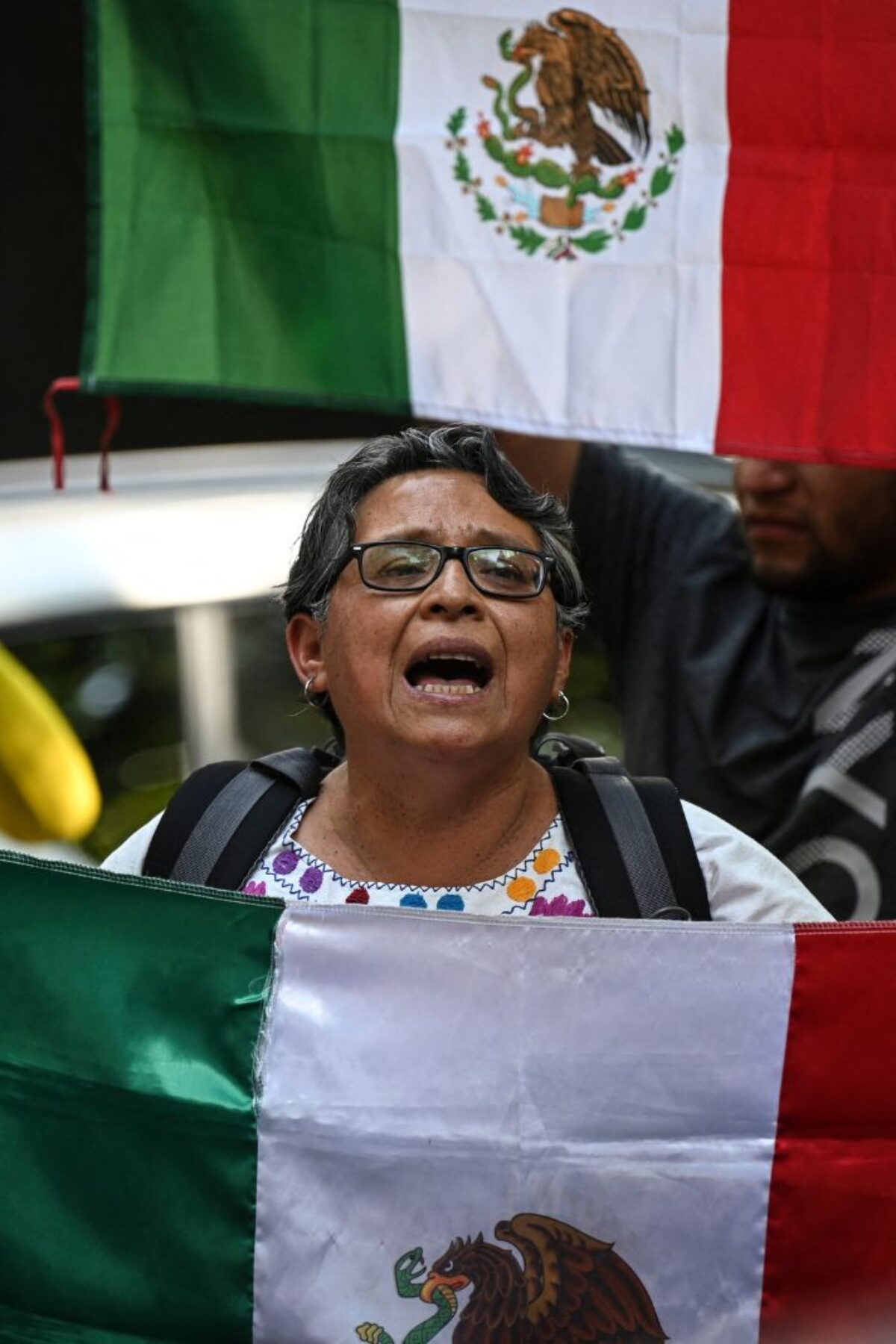 People holding Mexican flags protest outside the Ecuadorian embassy in Mexico City on April 6, 2024, following the severance of diplomatic relations between the Ecuador and Mexico. Ecuadorian authorities stormed the Mexican embassy in Quito on April 5 to arrest former vice president Jorge Glas, who had been granted political asylum there, prompting Mexico to sever diplomatic ties after the 