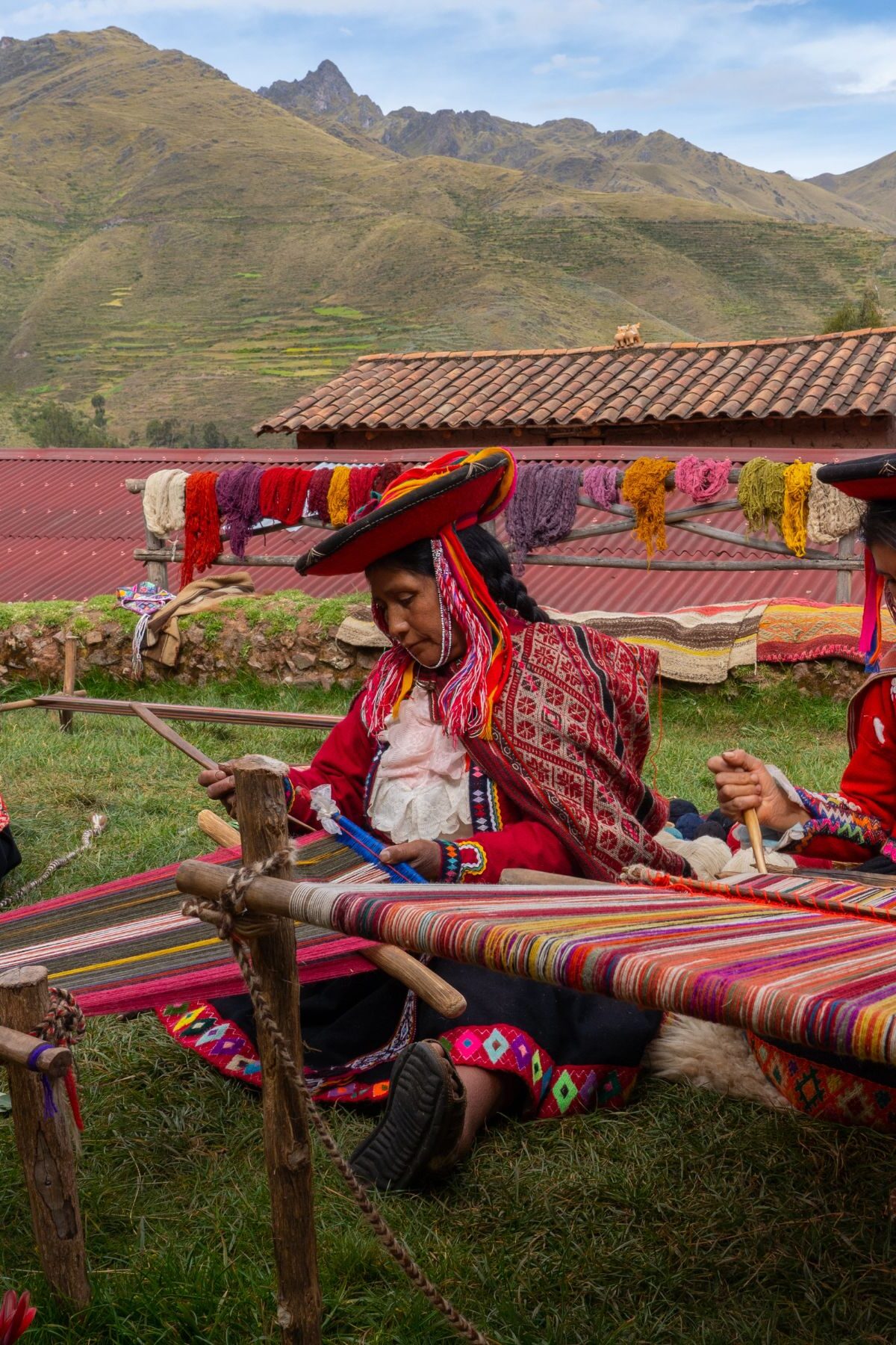 Three local female weavers in colourful traditional local dress including festooned hats, weaving colourful alpaca wool on the ground, Chumbe Community, Lamay, Sacred Valley, Peru (3 Model Releases and Property Release) - stock photo