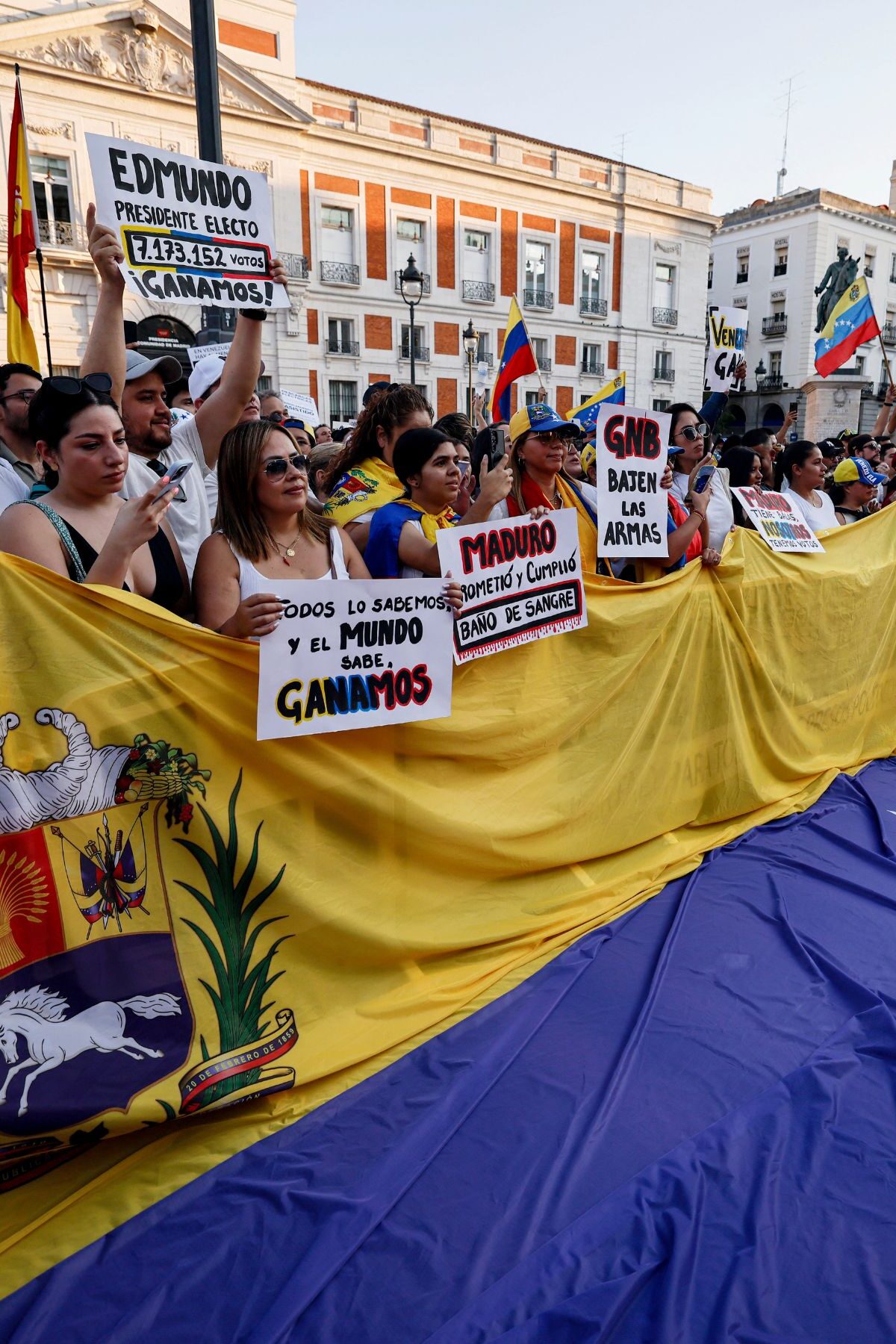 Demonstrators hold a giant national flag of Venezuela during a protest against Venezuelan President Nicolas Maduro's disputed victory in the country's Presidential elections, at Puerta del Sol, Madrid, on August 3, 2024. (Photo by OSCAR DEL POZO / AFP) (Photo by OSCAR DEL POZO/AFP via Getty Images)