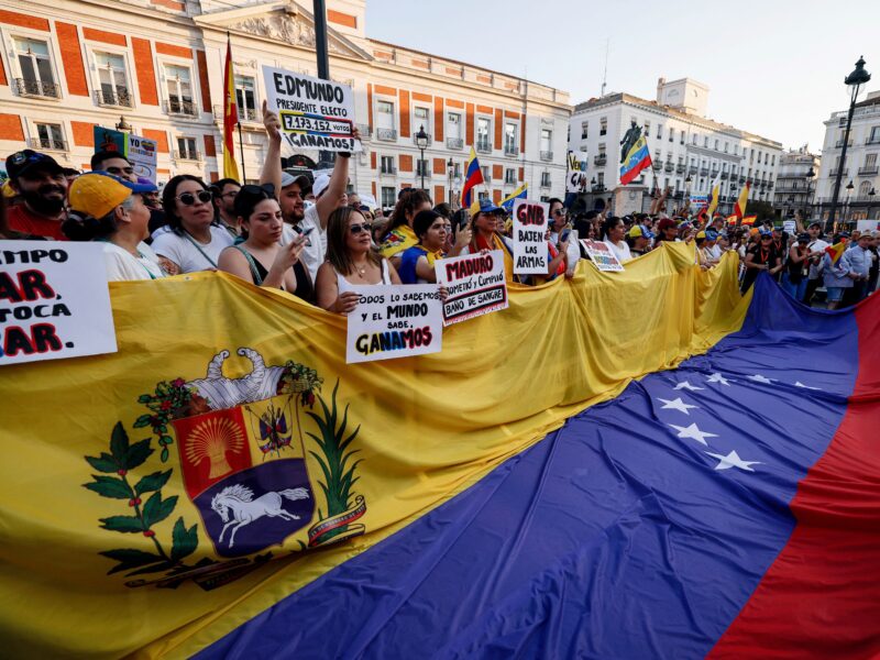 Demonstrators hold a giant national flag of Venezuela during a protest against Venezuelan President Nicolas Maduro's disputed victory in the country's Presidential elections, at Puerta del Sol, Madrid, on August 3, 2024. (Photo by OSCAR DEL POZO / AFP) (Photo by OSCAR DEL POZO/AFP via Getty Images)