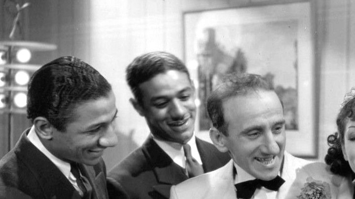Photo of Jimmy Durante, Lupe Vélez and the Mills Brothers from the 1934 film ''Strictly Dynamite''. This work is in the public domain.