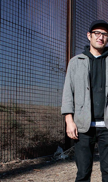 Multimedia artist Zeke Peña next to the El Paso-Júarez border fence. Photo by Itzel Alejandra Martinez