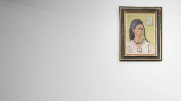 A member of the gallery team poses with "Autorretrato" by artist Frida Kahlo at the Ordovas gallery in London, England.   Photo by Leon Neal/Getty Images News