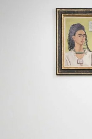 A member of the gallery team poses with "Autorretrato" by artist Frida Kahlo at the Ordovas gallery in London, England.   Photo by Leon Neal/Getty Images News