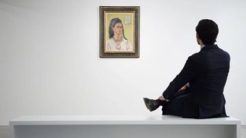 A member of the gallery team poses with "Autorretrato" by artist Frida Kahlo at the Ordovas gallery in London, England.   Photo by Leon Neal/Getty Images News
