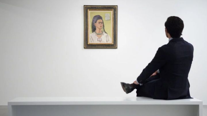 A member of the gallery team poses with "Autorretrato" by artist Frida Kahlo at the Ordovas gallery in London, England.   Photo by Leon Neal/Getty Images News