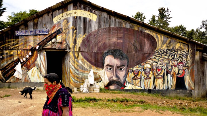 A woman, with face covered, passes by a mural painting in the Oventic village in Chiapas, run by Zapatistas.
Photo by Dekaro / iStock Editorial / Getty Images Plus