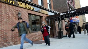 People walk past the Peter Luger steakhouse December 29, 2003 in New York City. Photo by Spencer Platt/Getty Images News