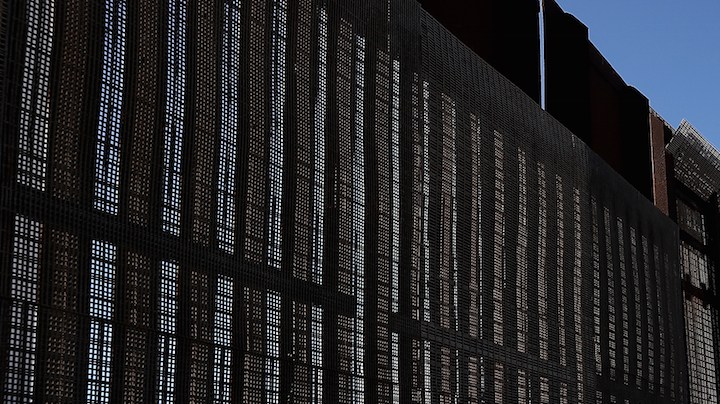 A man stands next to the U.S.-Mexico border fence at Friends of Friendship Park on February 4, 2017 in San Ysidro, California. Photo by Justin Sullivan/Getty Images  News