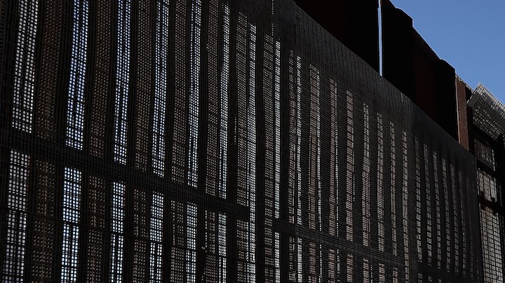 A man stands next to the U.S.-Mexico border fence at Friends of Friendship Park on February 4, 2017 in San Ysidro, California. Photo by Justin Sullivan/Getty Images  News