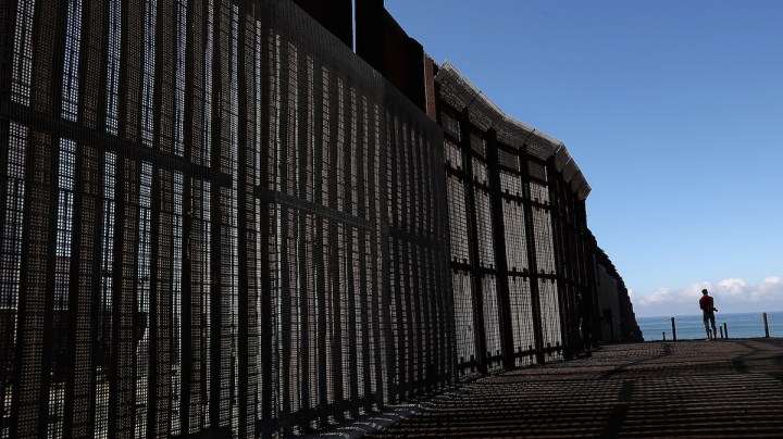 A man stands next to the U.S.-Mexico border fence at Friends of Friendship Park on February 4, 2017 in San Ysidro, California. Photo by Justin Sullivan/Getty Images News