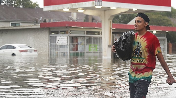 People walk down a flooded street as they evacuate their homes after the area was inundated with flooding from Hurricane Harvey on August 27, 2017 in Houston, Texas. Harvey, which made landfall north of Corpus Christi late Friday evening, is expected to dump upwards to 40 inches of rain in Texas over the next couple of days. Photo by Joe Raedle/Getty Images