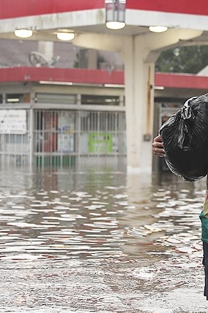People walk down a flooded street as they evacuate their homes after the area was inundated with flooding from Hurricane Harvey on August 27, 2017 in Houston, Texas. Harvey, which made landfall north of Corpus Christi late Friday evening, is expected to dump upwards to 40 inches of rain in Texas over the next couple of days. Photo by Joe Raedle/Getty Images