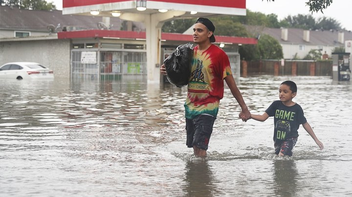 People walk down a flooded street as they evacuate their homes after the area was inundated with flooding from Hurricane Harvey on August 27, 2017 in Houston, Texas. Harvey, which made landfall north of Corpus Christi late Friday evening, is expected to dump upwards to 40 inches of rain in Texas over the next couple of days. Photo by Joe Raedle/Getty Images