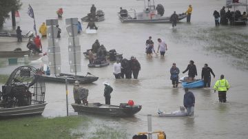 People walk down a flooded street as they evacuate their homes after the area was inundated with flooding from Hurricane Harvey on August 28, 2017 in Houston, Texas. Harvey, which made landfall north of Corpus Christi late Friday evening, is expected to dump upwards to 40 inches of rain in Texas over the next couple of days. Photo by Joe Raedle/Getty Images
