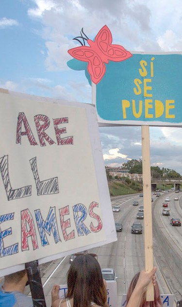 People hold signs over the 110 freeway as thousands of immigrants and supporters join the Defend DACA March to oppose the President Trump order to end DACA on September 10, 2017 in Los Angeles, California. Photo by David McNew/Getty Images News