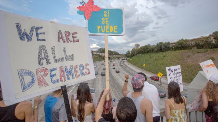 People hold signs over the 110 freeway as thousands of immigrants and supporters join the Defend DACA March to oppose the President Trump order to end DACA on September 10, 2017 in Los Angeles, California. Photo by David McNew/Getty Images News