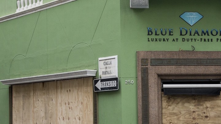 A woman passes a boarded up business as residents prepare for a direct hit from Hurricane Maria on September 19, 2017 in San Juan, Puerto Rico. Photo by Alex Wroblewski/Getty Images News
