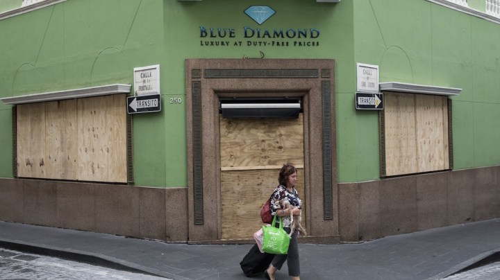 A woman passes a boarded up business as residents prepare for a direct hit from Hurricane Maria on September 19, 2017 in San Juan, Puerto Rico. Photo by Alex Wroblewski/Getty Images News