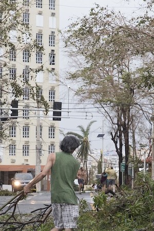 A resident cleans brush from the street in the Miramar neighborhood after Hurricane Maria made landfall on September 20, 2017 in San Juan, Puerto Rico. Photo by Alex Wroblewski/Getty Images  News