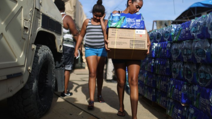 A resident carries food and water, provided by FEMA, in a neighborhood without grid electricity or running water on October 17, 2017 in San Isidro, Puerto Rico. Photo by Mario Tama/Getty Images