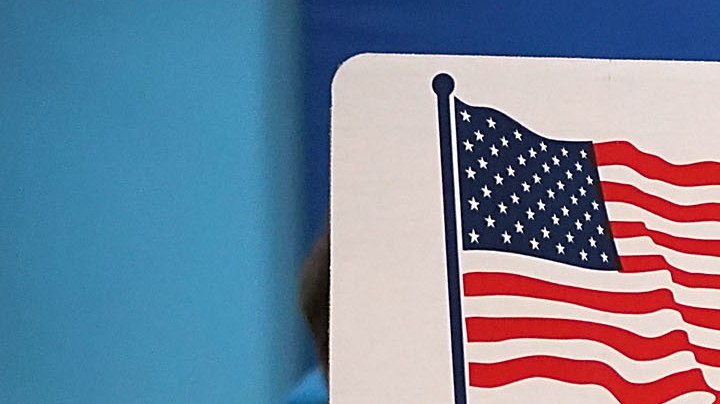 Karina Smith holds her 2-year-old son Kyler as she fills out her ballot at the polling place at Washington Mill Elementary School. Photo by Chip Somodevilla/Getty Images News