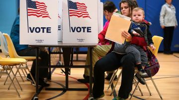 Karina Smith holds her 2-year-old son Kyler as she fills out her ballot at the polling place at Washington Mill Elementary School. Photo by Chip Somodevilla/Getty Images News