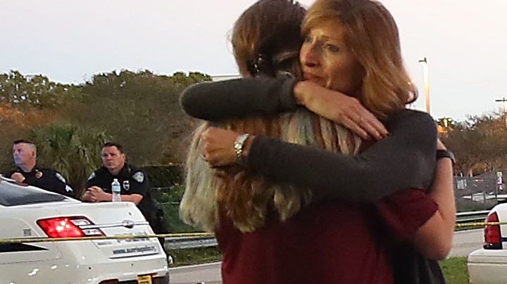 Kristi Gilroy (R), hugs a young woman at a police check point near the Marjory Stoneman Douglas High School where 17 people were killed by a gunman yesterday, on February 15, 2018 in Parkland, Florida. Police arrested the suspect after a short manhunt, and have identified him as 19-year-old former student Nikolas Cruz.  Photo by Mark Wilson/Getty Images