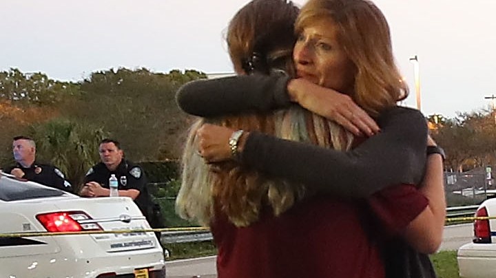 Kristi Gilroy (R), hugs a young woman at a police check point near the Marjory Stoneman Douglas High School where 17 people were killed by a gunman yesterday, on February 15, 2018 in Parkland, Florida. Police arrested the suspect after a short manhunt, and have identified him as 19-year-old former student Nikolas Cruz.  Photo by Mark Wilson/Getty Images