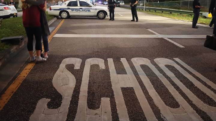 Kristi Gilroy (R), hugs a young woman at a police check point near the Marjory Stoneman Douglas High School where 17 people were killed by a gunman yesterday, on February 15, 2018 in Parkland, Florida. Police arrested the suspect after a short manhunt, and have identified him as 19-year-old former student Nikolas Cruz. Photo by Mark Wilson/Getty Images