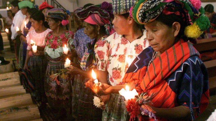 Guatemalan Mayan Quiche Indian women pray as they burn candles around 41 coffins of victims, found in a 1980's clandestine cemetery. Photo by Andrea Nieto/Getty Images