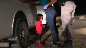 A two-year-old Honduran asylum seeker cries as her mother is searched and detained near the U.S.-Mexico border.  Photo by John Moore/Getty Images