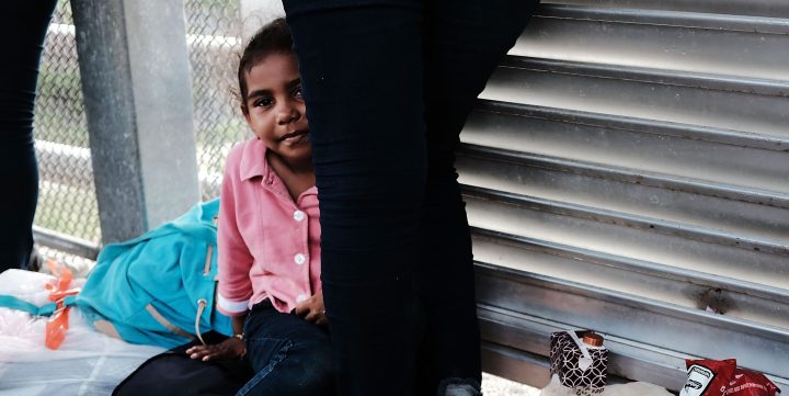 A Honduran girl, fleeing poverty and violence in her home country, waits with her mother along the border bridge after being denied into the Texas city of Brownsville. Photo by Spencer Platt/Getty Images