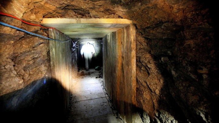 An investigator combs through a drug tunnel found in a warehouse in Otay Mesa, California. Photo by Sandy Huffaker/Getty Images